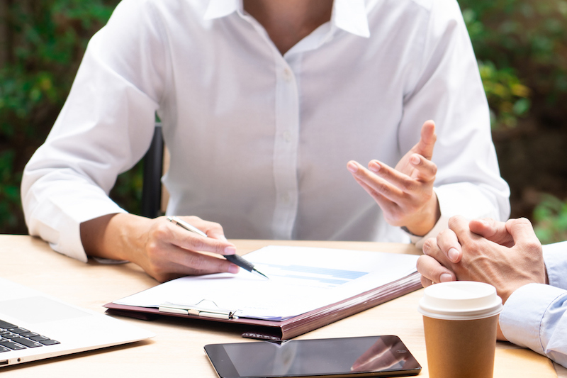 Two asian business coworkers outside office buildings discuss and commenting work to each other. Two asian business coworkers outside office buildings discuss and commenting work to each other.