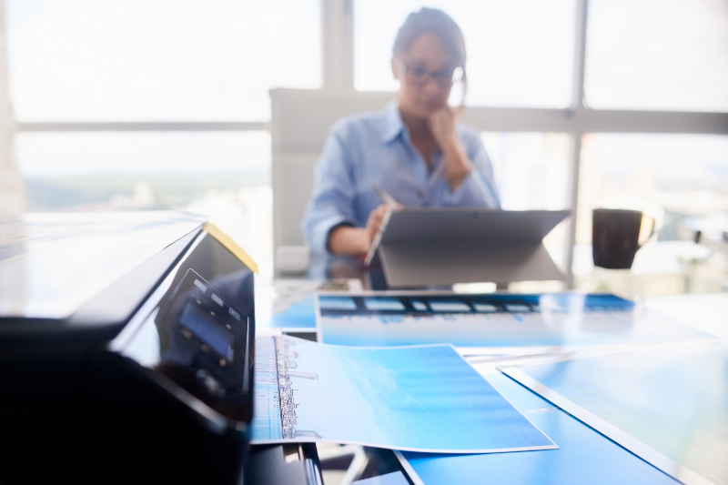 close up of printer in foreground worker in background