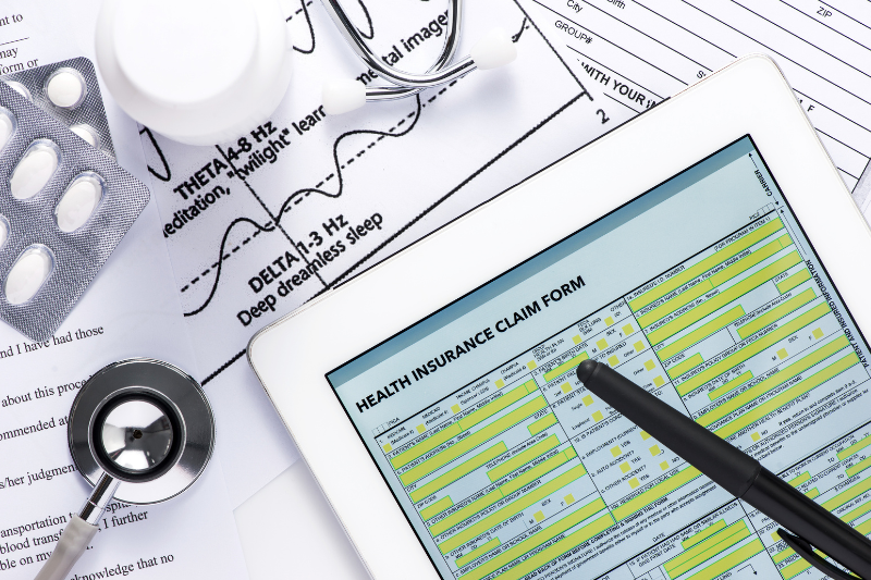 electronic health insurance claim form on a tablet with pills and stethoscope