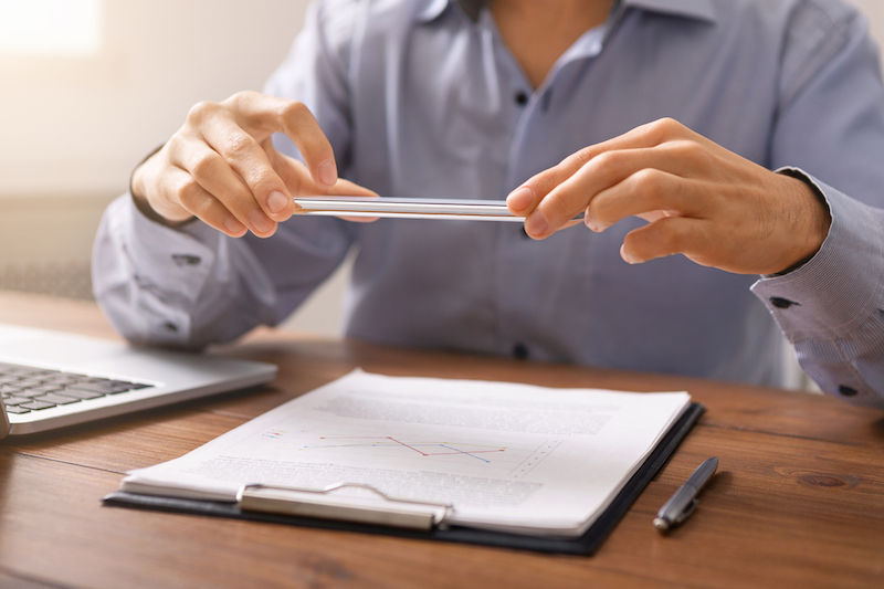 Unrecognizable man scanning documents in office using scanner app on smartphone at workplace