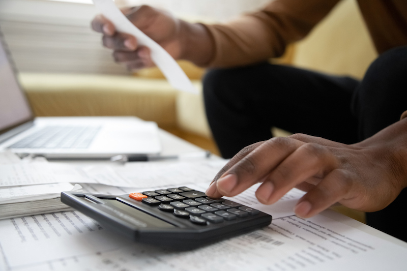 Close up of african american man with calculator checking bills Close up of african american man with calculator checking bills
