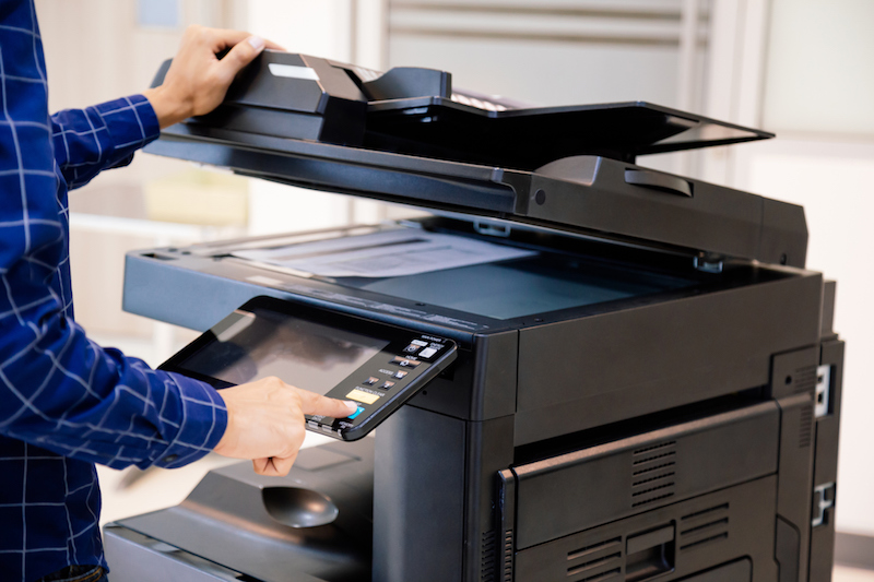 Businessmen press button on the panel for using photocopier or printer for printout and scanning document paper at office.