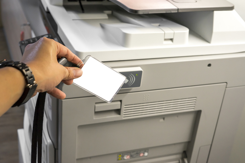 man hold card for scanning key card to access Photocopier