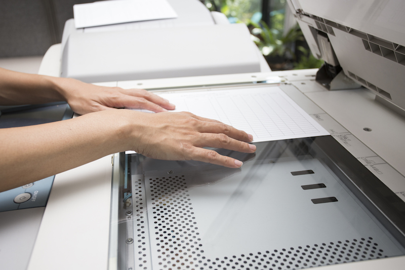 woman hands putting a sheet of paper into a copying device woman hands putting a sheet of paper into a copying device