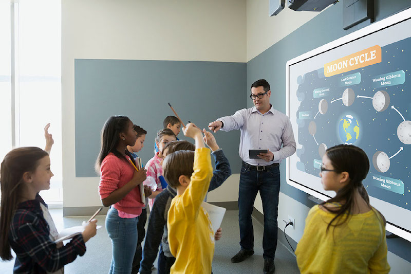 Teacher using IWB to teach students about solar system in classroom