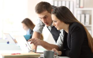 Two business people reading a computer screen signifying Microsoft Office 365 Services