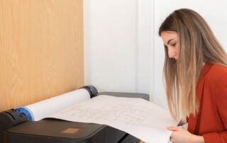 Woman reviewing blueprints that are being printed from a wide format printer.