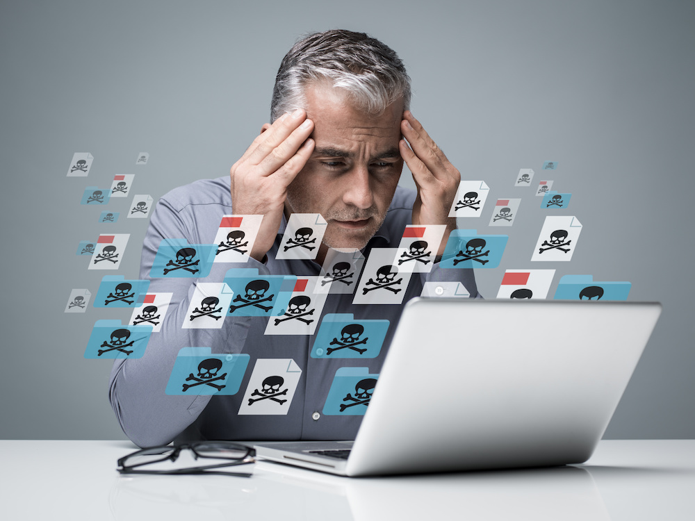 Businessman working with a computer full of viruses, infected files and malwares: he is frustrated with head in hands
