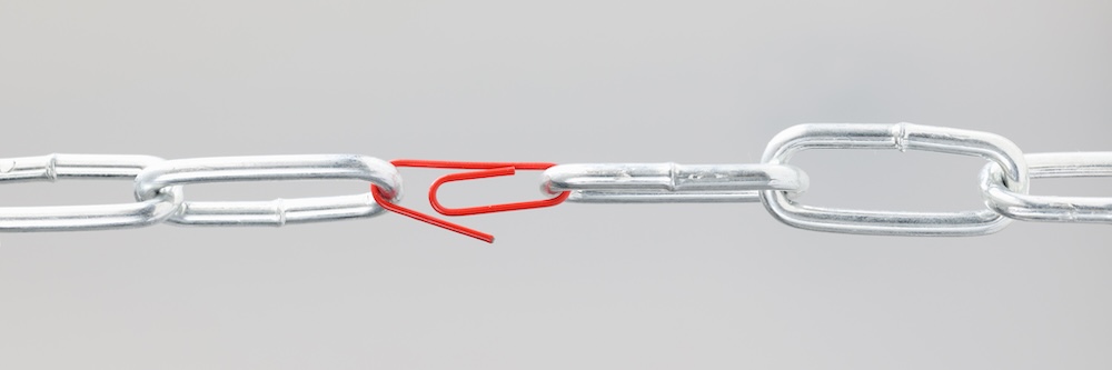 Chrome chain in middle with red paper clip. Broken chain linked by paper clip concept. Poor document security concept.