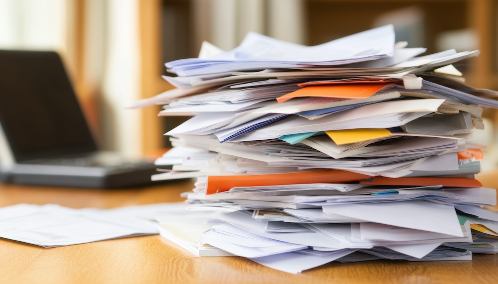 a cluttered pile of paper showing the need for document management