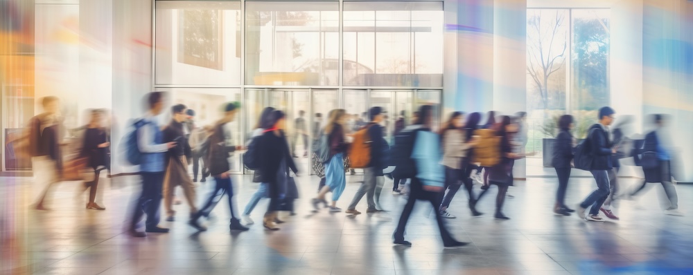 Students walking to class in a university or college environment. Moving crowd motion blurred background. 