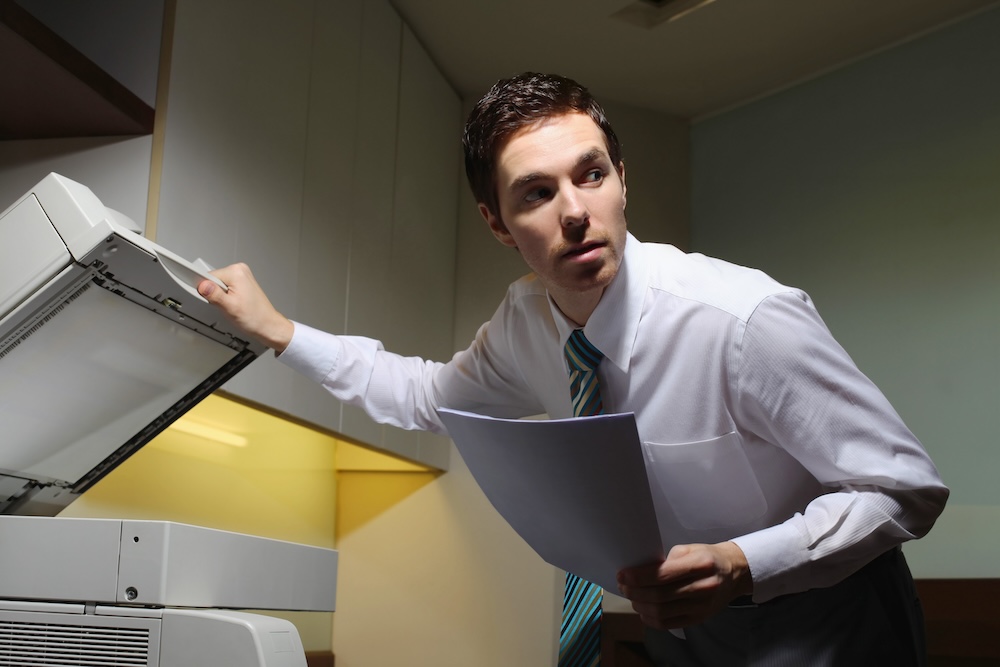 business person stealing documents from printer